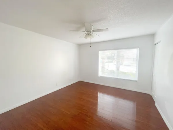 an empty room with a window and a ceiling fan