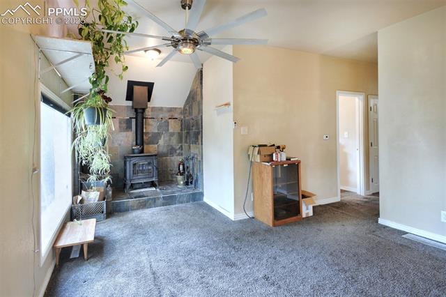 46 Sunflower Road Colorado Springs, CO 80907 - Photo 12 of 35 Living area with carpet, a wood stove, ceiling fan, baseboards, and vaulted ceiling