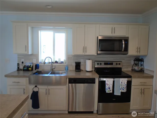 a kitchen with stainless steel appliances granite countertop a stove a sink and a microwave
