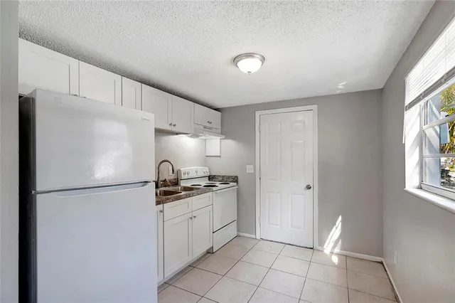 a kitchen with granite countertop a refrigerator and a stove top oven