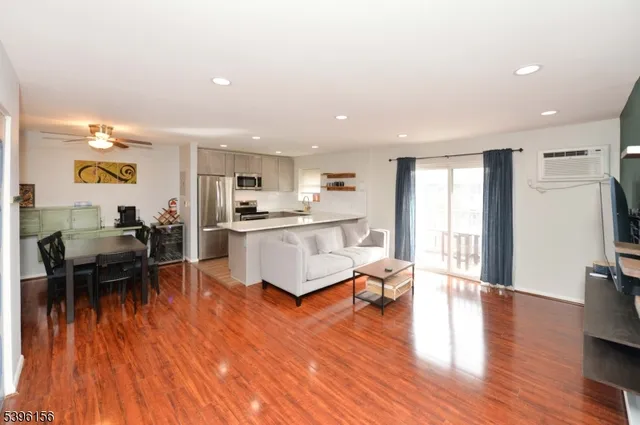 a living room with stainless steel appliances kitchen island hardwood floor and a view of kitchen