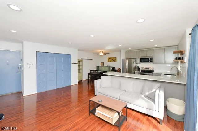 a living room with stainless steel appliances kitchen island granite countertop a living room view and wooden floor