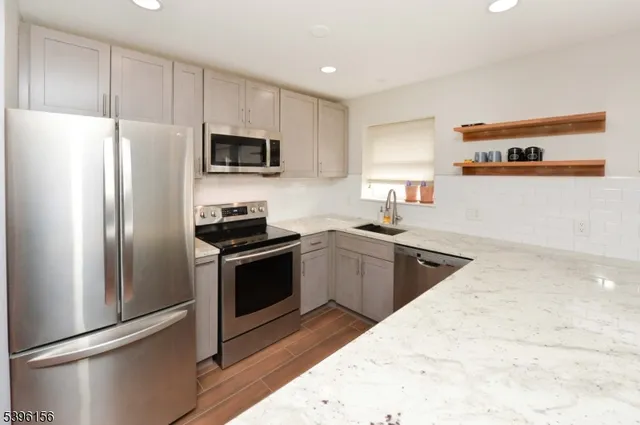 a kitchen with stainless steel appliances granite countertop a refrigerator stove top oven and sink