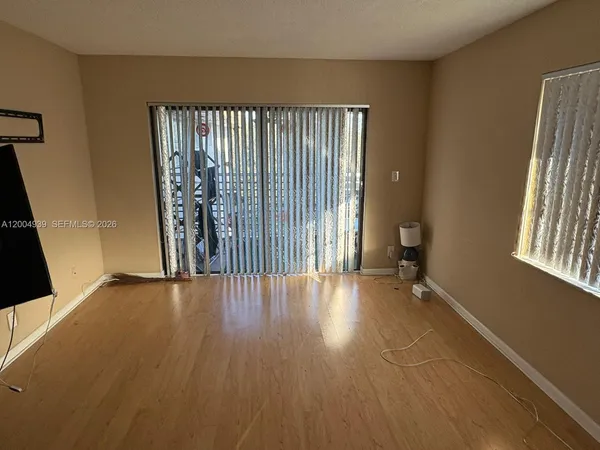 an empty room with wooden floor and windows