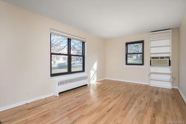 an empty room with wooden floor cabinet and windows
