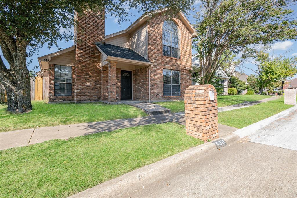 Traditional home featuring a front lawn, a chimney, brick siding, and roof with shingles