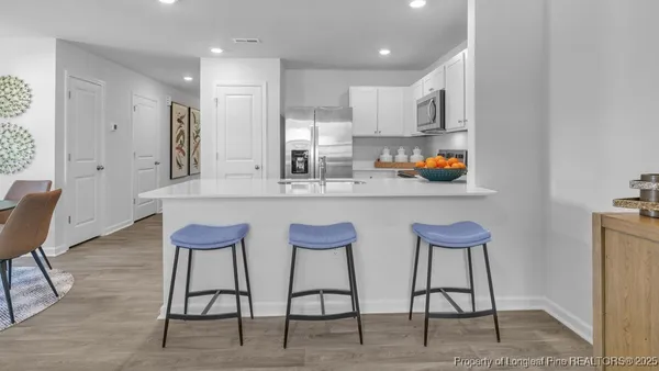 a kitchen with stainless steel appliances kitchen island granite countertop a dining table chairs and a refrigerator