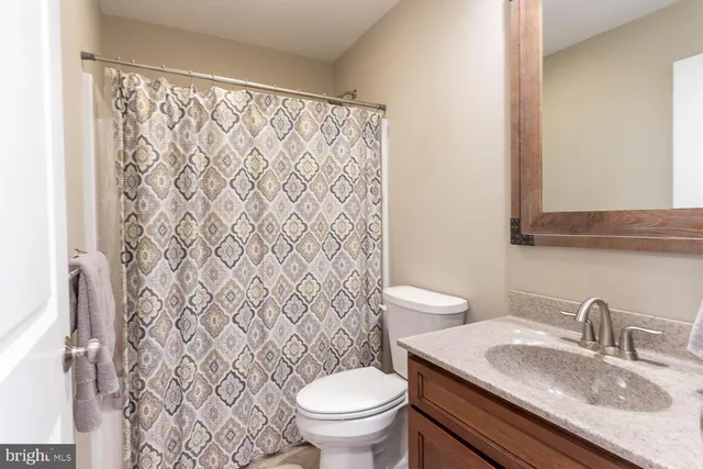 a bathroom with a granite countertop sink toilet and a mirror