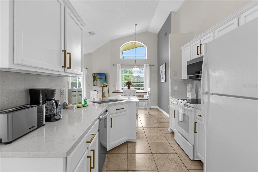 217 Holborn Loop Davenport, FL 33897 - Photo 4 of 23 a large white kitchen with stainless steel appliances granite countertop a lot of counter top space