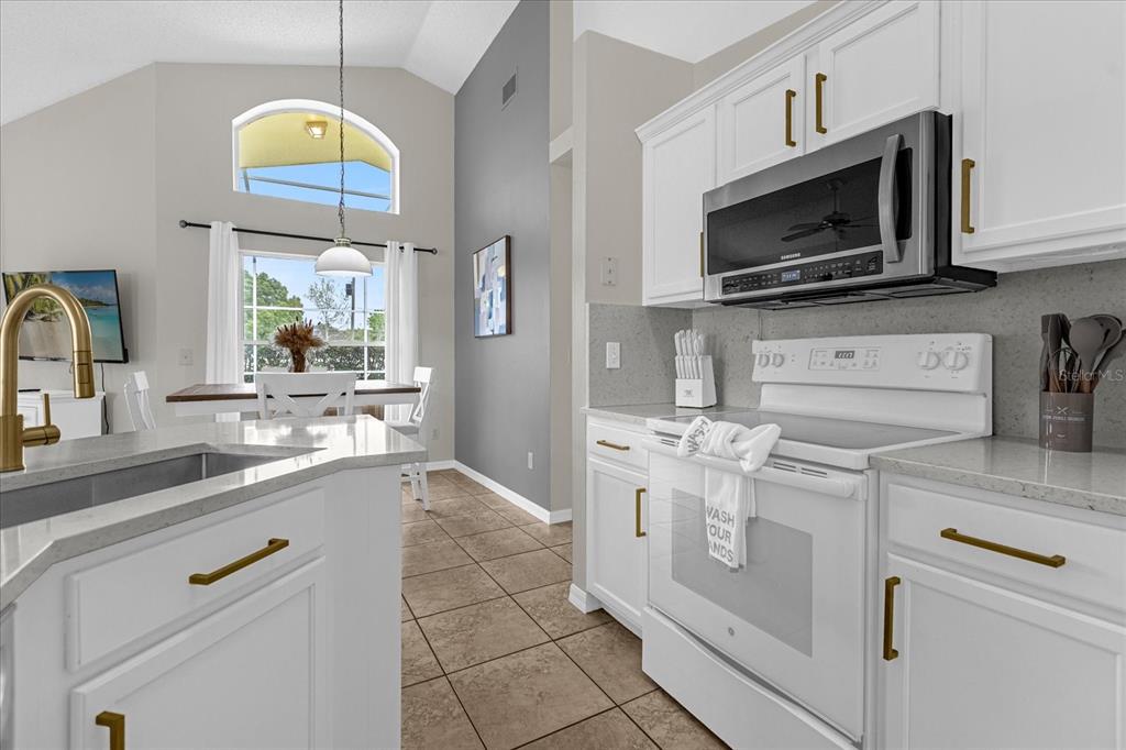 217 Holborn Loop Davenport, FL 33897 - Photo 6 of 23 a kitchen with stainless steel appliances granite countertop a stove a sink and a microwave