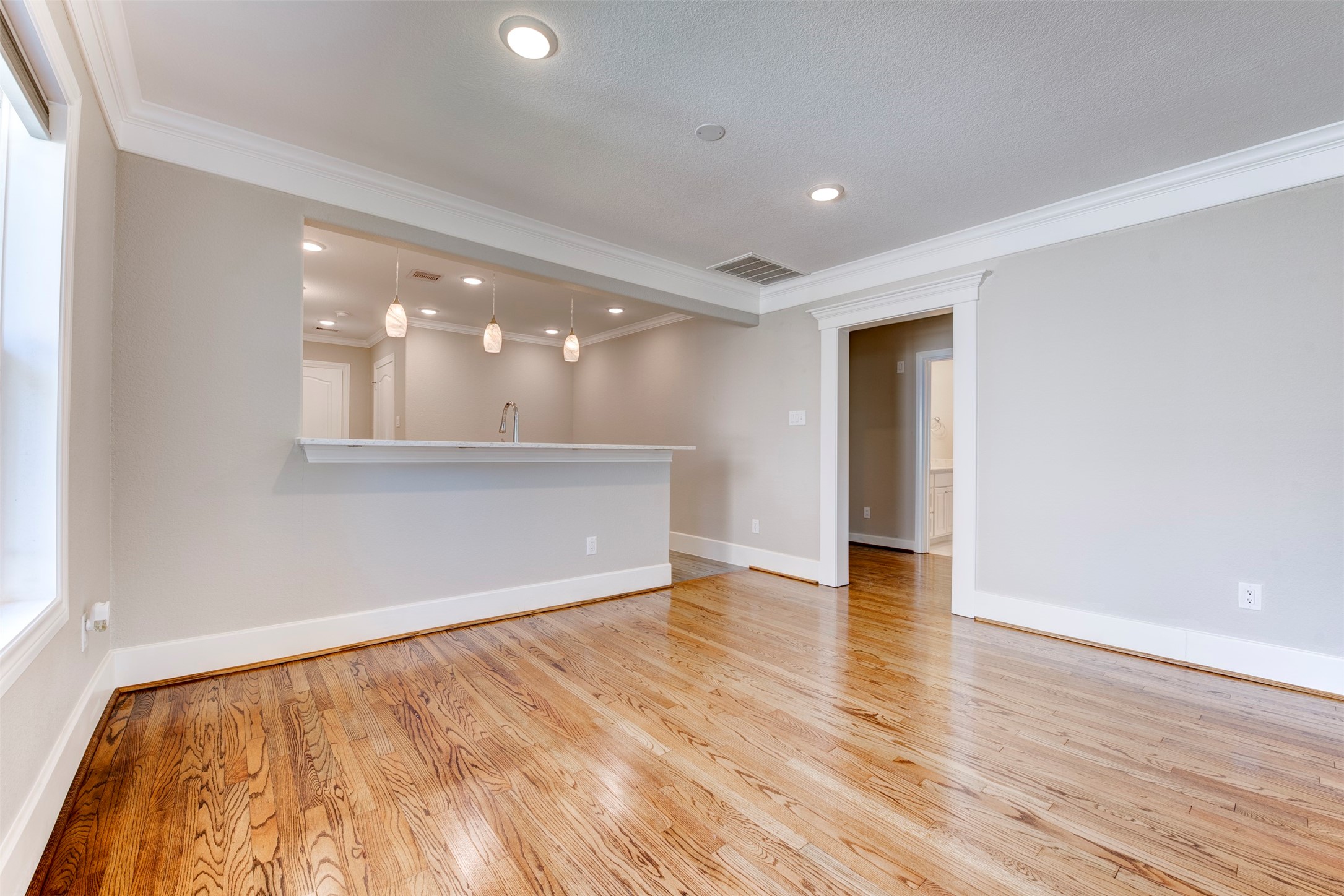 109 Dresden Street Houston, TX 77012 - Photo 13 of 43 This room features hardwood floors, recessed lighting, and a modern open layout with a kitchen bar. Neutral walls and large windows provide a bright, spacious feel.