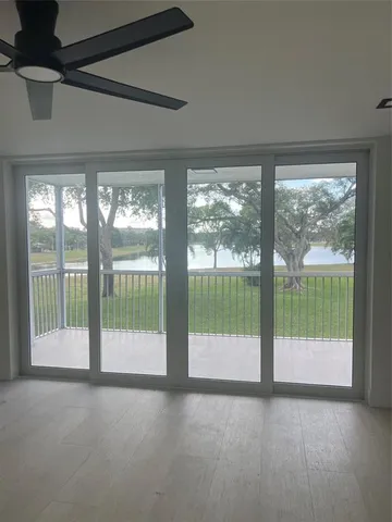 a view of an empty room with wooden floor and a balcony