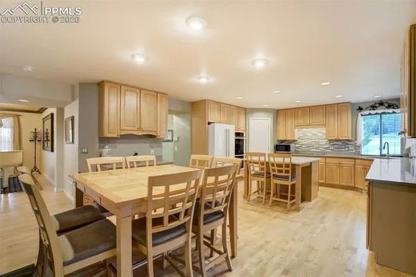 a kitchen with stainless steel appliances kitchen island granite countertop a dining table chairs and white cabinets