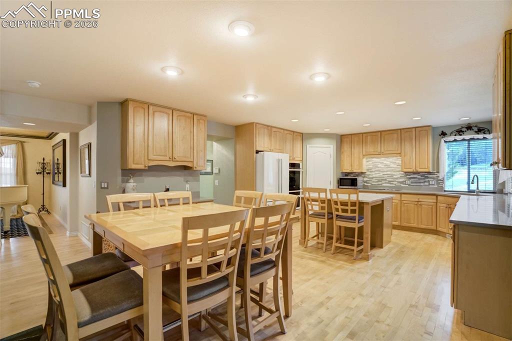 4618 Bethany Court Colorado Springs, CO 80918 - Photo 7 of 50 a kitchen with stainless steel appliances kitchen island granite countertop a dining table chairs and white cabinets
