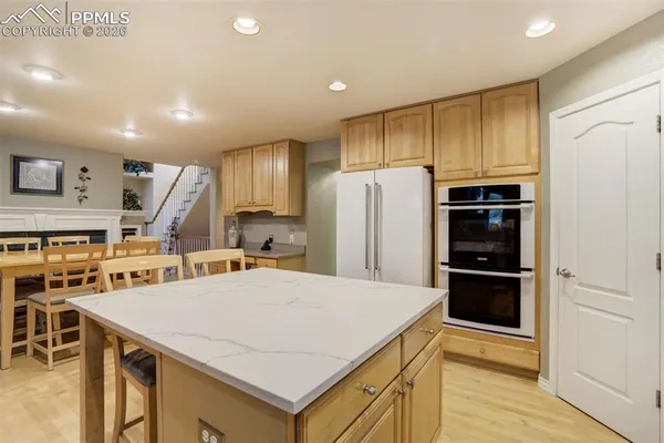 a kitchen with refrigerator and chairs
