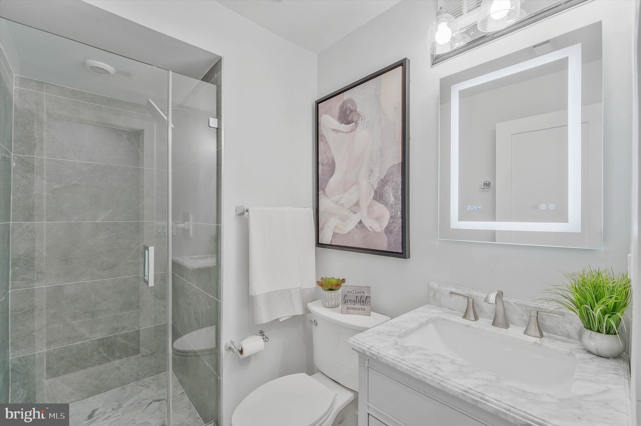 1240 Columbia Road Northwest, Unit 1 Washington, DC 20009 - Photo 13 of 25 a bathroom with a granite countertop toilet sink and mirror