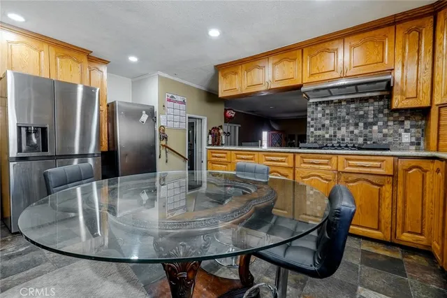 a kitchen with stainless steel appliances granite countertop a table chairs in it and granite top