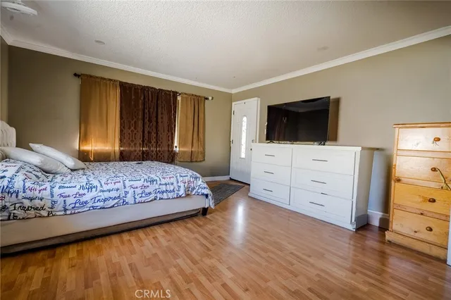 a bedroom with a bed and a flat tv screen on dresser