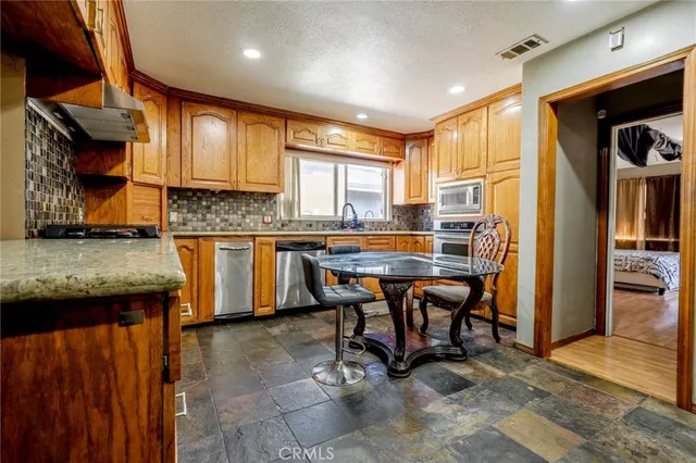 a kitchen with stainless steel appliances granite countertop table chairs sink and cabinets