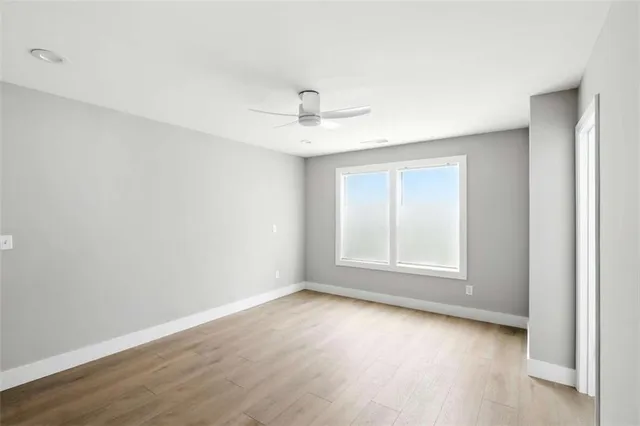 an empty room with wooden floor and ceiling fan