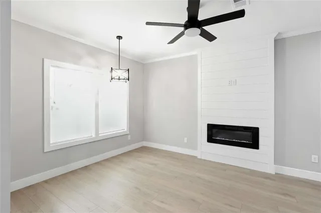 a view of an empty room with a window and kitchen view