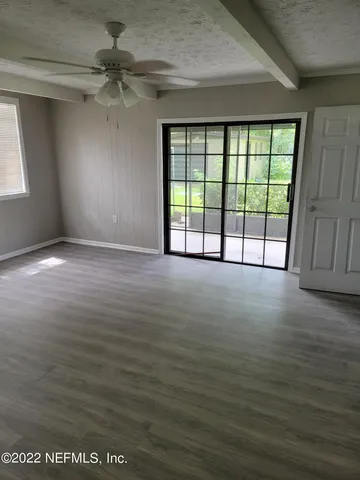 en empty room with windows and ceiling fan