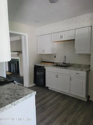 a kitchen with granite countertop white cabinets and stainless steel appliances