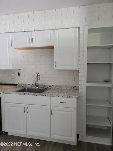 a kitchen with granite countertop white cabinets and a stove