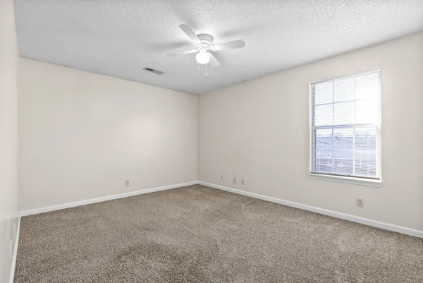 an empty room with windows and ceiling fan