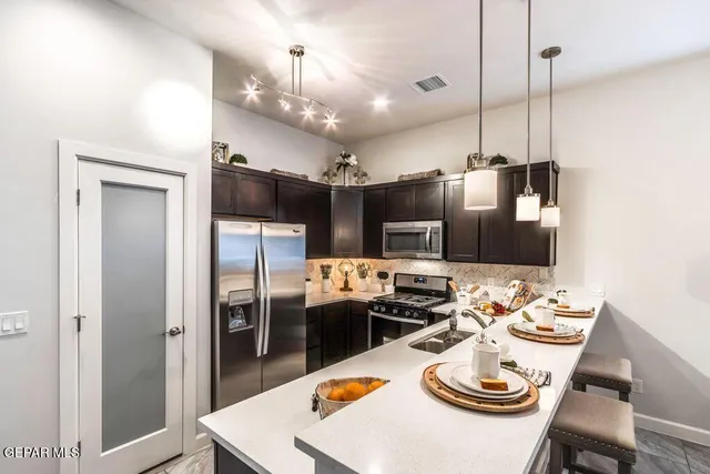 a kitchen with stainless steel appliances kitchen island granite countertop a dining table and chairs
