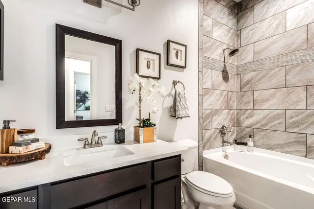 a bathroom with a granite countertop sink toilet a mirror a vanity a bath tub and shower