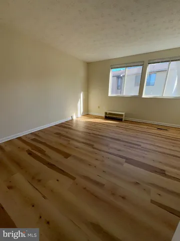 a view of a room with wooden floor and bench in it