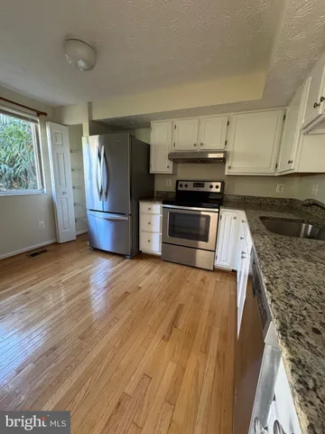 a kitchen with granite countertop a stove and a wooden floors
