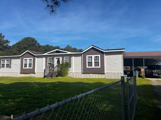 Manufactured / mobile home with an attached carport, fence, and a front lawn