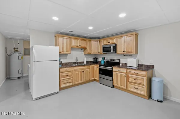 a kitchen with stainless steel appliances granite countertop a stove top oven a sink dishwasher a dining table and chairs with wooden floor