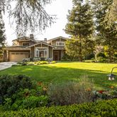 a view of a house with a big yard and large trees