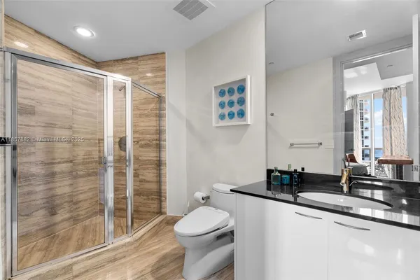 a bathroom with a granite countertop sink toilet and shower