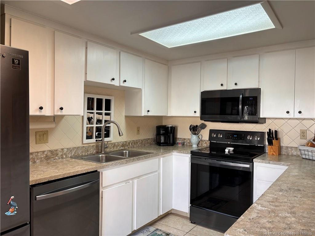 3828 Jefferson Street Stuart, FL 34997 - Photo 6 of 15 a kitchen with granite countertop a sink stainless steel appliances and white cabinets