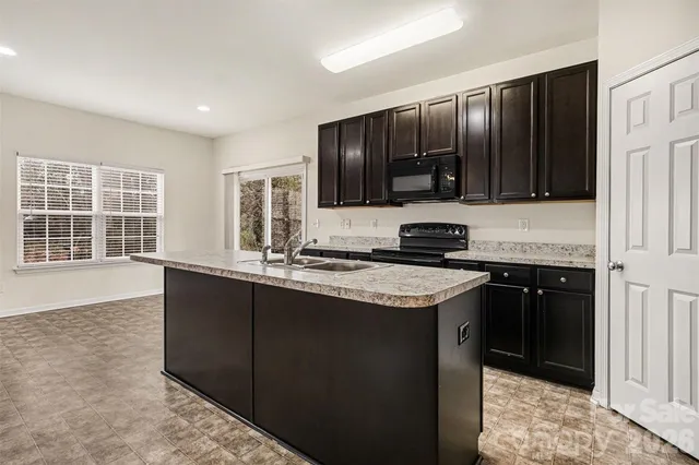 a kitchen with granite countertop a stove top oven sink and cabinets