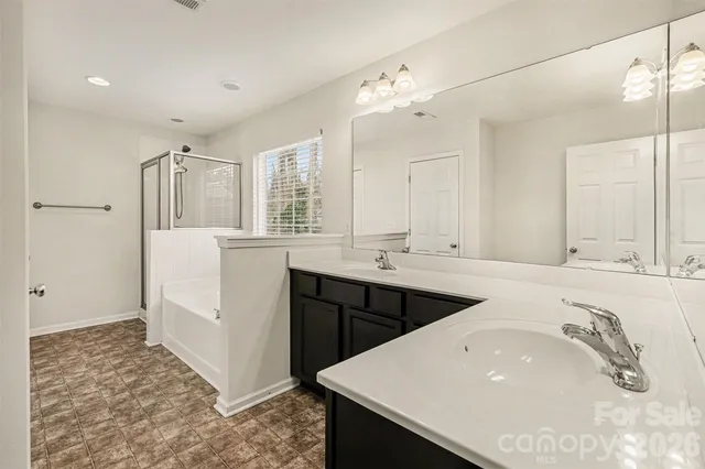 a spacious bathroom with a double vanity sink a mirror and shower