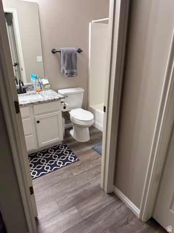 14797 South Chandlerpoint Way Draper, UT 84020 - Photo 26 of 33 Bathroom featuring wood-finish flooring, a white vanity with granite-style countertop, an undermount sink with a black faucet, and a white shower-tub combination