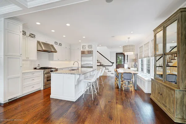 a kitchen with a island wooden floors appliances and white cabinets