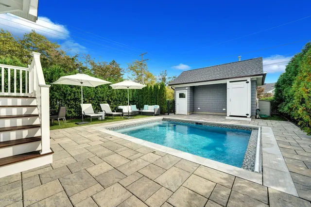 a view of pool with lawn chairs under an umbrella