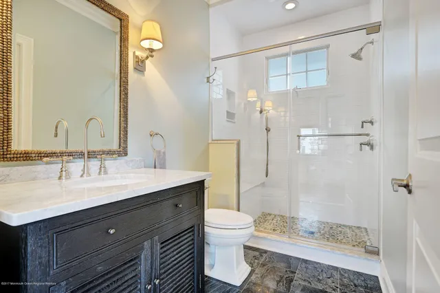 a bathroom with a granite countertop sink toilet a mirror and shower