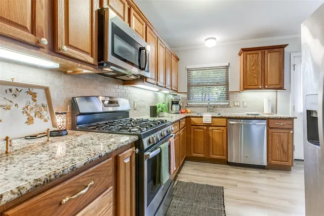 a kitchen with stainless steel appliances granite countertop a stove a sink and a microwave