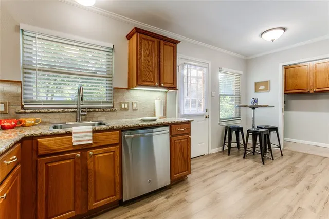 a kitchen with stainless steel appliances granite countertop wooden floor a sink a stove a dining table and chairs