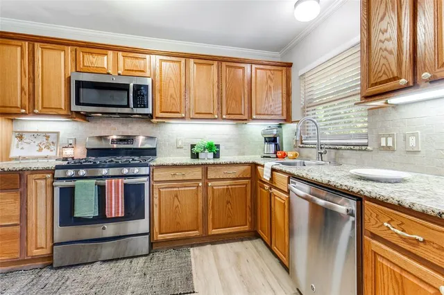 a kitchen with stainless steel appliances granite countertop a stove a sink and a microwave