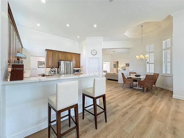 a dining room with wooden floor a chandelier a glass table and chairs