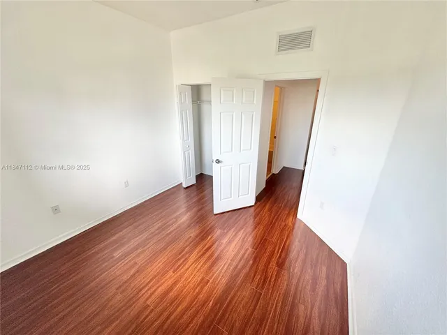 an empty room with wooden floor and closet