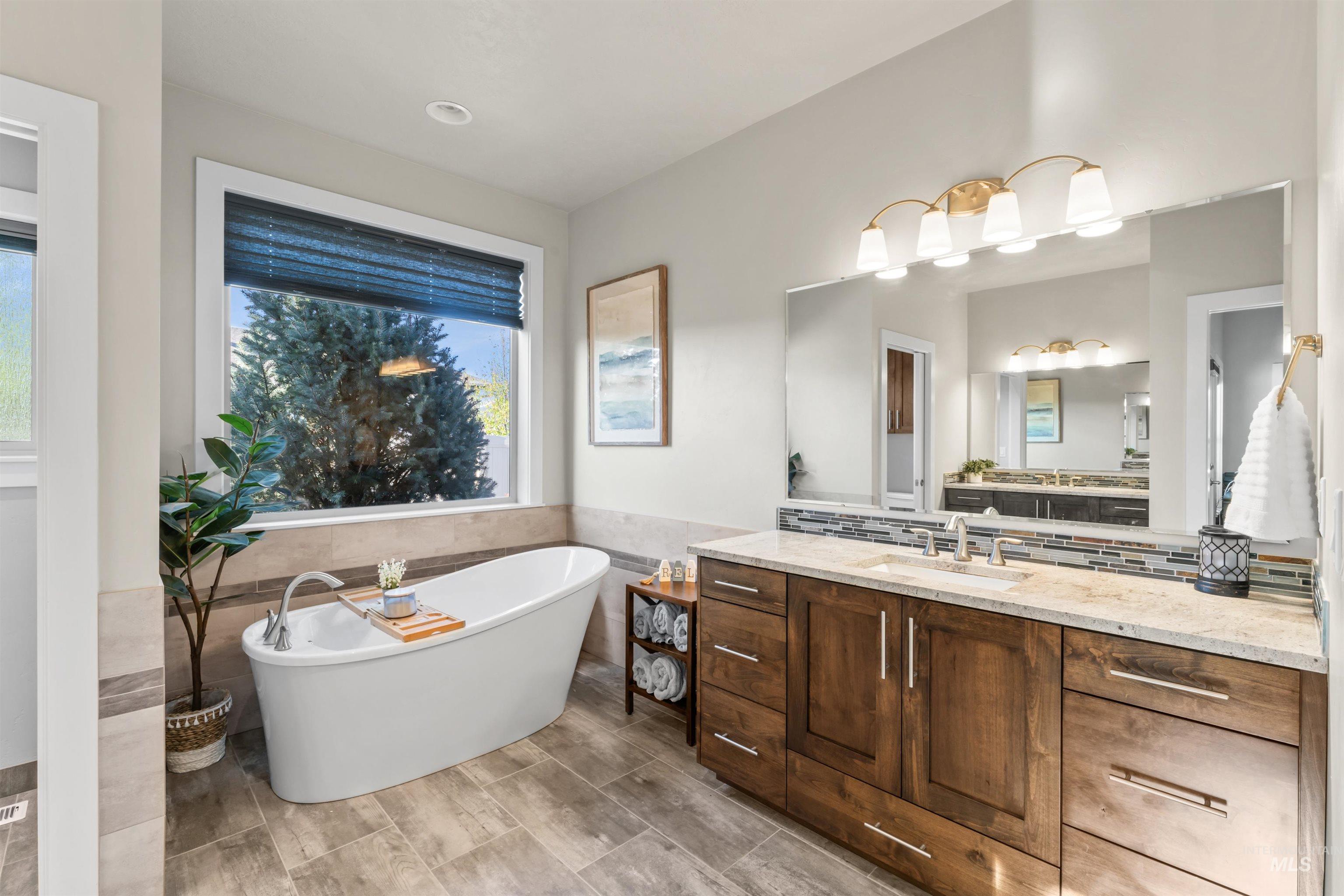 12356 West Rice Road Star, ID 83669 - Photo 20 of 49 Full bath featuring tile walls, a freestanding tub, vanity, wainscoting, and tasteful backsplash
